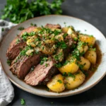 Sliced tender chuck roast with baby potatoes, topped with onions and fresh parsley on a rustic plate.